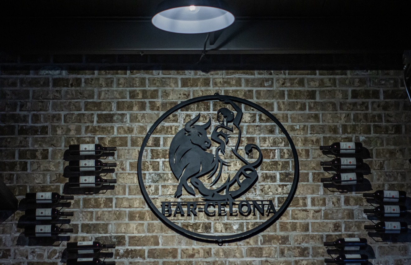 Bar-Celona metal logo and wine display on brick wall
